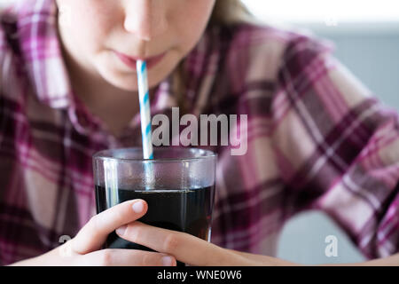 In der Nähe von Mädchen Trinken von zuckerhaltigen Fizzy Soda aus Glas mit Strohhalm Stockfoto