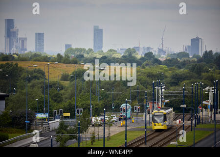 Metrolink tram in Ashton-under-Lyne Bestehen der Ashton Moss Freizeitpark (Verdeckt) mit Manchester City Skyline hinter Stockfoto