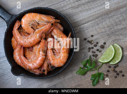 Gegrillte Garnelen Garnelen in einer Pfanne mit Gewürzen, auf Holz- Hintergrund. Ansicht von oben. Stockfoto