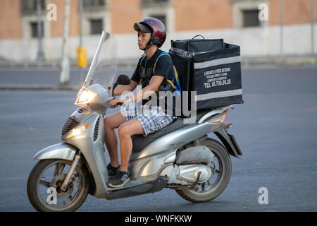 Rom, Italien, 18. August 2019: ein Junge auf einem Roller, er Transporte Essen zu sich nach Hause geliefert werden. In den Straßen der Stadt. Stockfoto