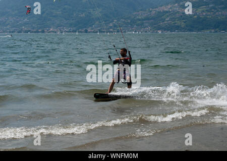 Comer see, Italien - Juli 21., 2019. Wasser sport: Kitesurfer Reiten auf einem sonnigen Sommertag in der Nähe der Colico, Stadt in Italien. Alp Berge auf Stockfoto