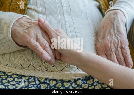 Closeup weibliche Hand, die eine faltige Hand einer älteren Frau Stockfoto