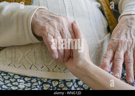 Closeup weibliche Hand, die eine faltige Hand einer älteren Frau Stockfoto