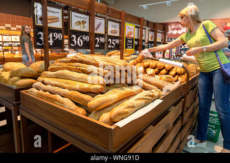 Eine Frau kauft Baguettes in eine Bäckerei. frische Produkte wählt der Käufer Stockfoto