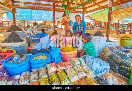 KAKKU, MYANMAR - Februar 20, 2018: Die Familie von Bauern mit kleinen Kindern in der garküche von Kakku Markt; Kinder spielen unter Pakete mit Nudeln, Ba Stockfoto