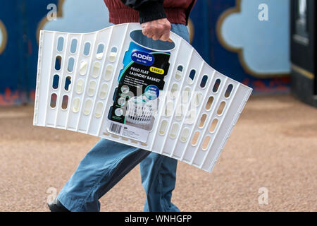 Mann, der weißen Kunststoff Addis flach zusammenfalten Wäschekorb, in Lytham St Annes, Großbritannien Stockfoto