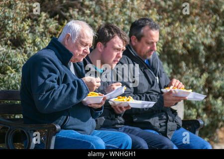 Drei Männer essen Fisch und chip Abendmahl in Lytham St Annes, Großbritannien Stockfoto