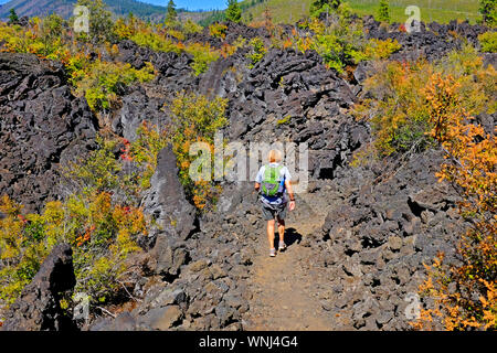 Eine weibliche Wanderer navigdates einen schmalen Waldweg durch eine Lava Bett in der Mount Jefferson Wüste, Cascade Mountains, Oregon. Stockfoto