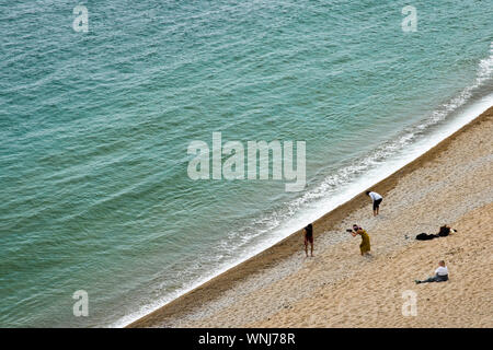 Touristen am Strand in der Nähe von Durdle Door, Dorset, England sitzen. Stockfoto