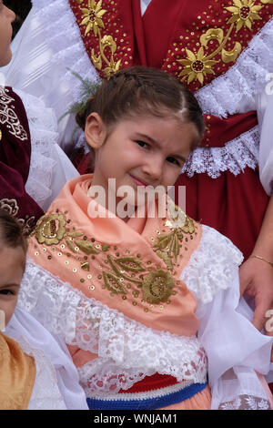 Mädchen gekleidet in traditionelle Kostüme am Thanksgiving Tag in Stitar, Kroatien an die Gemeinde in die Messe gehen Stockfoto