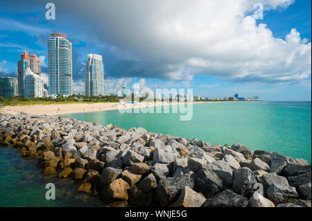 Hellen morgen Aussicht auf die Skyline von Miami South Beach mit einem Felsen Steg oben ruhigen türkisfarbenen Wasser stehend Stockfoto