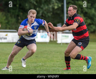 Junge männliche (Alter 20 Jahre) Bewunderer rugby spieler sprintet letzten Gegner, der von der Seite kommt, um einen Angriff zu Stockfoto