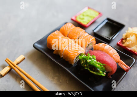 Ansicht von oben auf die traditionelle japanische leer mit Sushi, Ingwer, Sojasauce, Wasabi Schüssel und Essstäbchen auf Beton grau hinterlegt. Online asiatische Küche Stockfoto