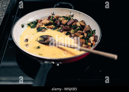 Frühstück im Dorf. Kochen Spinat mit Rührei in Rot pan. Stockfoto