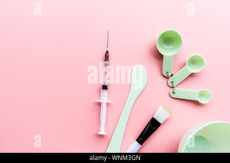 Tools und Injektor für zu Hause oder im Salon Gesichtspflege auf rosa Hintergrund, Ansicht von oben, flach. Serum, Maske. Mockup. Hautpflege Stockfoto