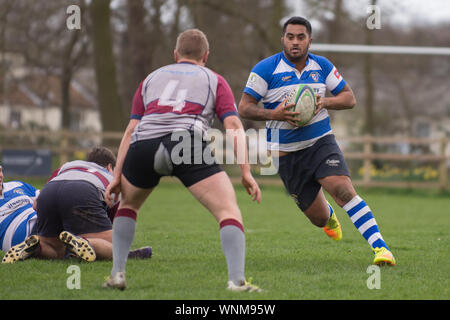 Blooper! Amateur Rugbyspieler spaltet seine Shorts, wie große Neuseeland Player läuft auf ihn zu den Ball in beiden Händen halten Stockfoto