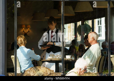 Kellnerin serviert ein Paar an einem Tisch in Bettys Tea Rooms, Harrogate, North Yorkshire, England, Großbritannien. Stockfoto