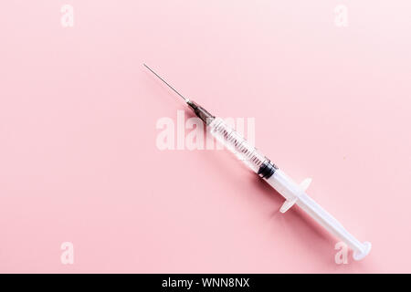 Medizinische Spritze auf rosa Hintergrund, Gesundheit und Impfung Konzept. Flach, Mockup, Overhead, Ansicht von oben und kopieren. Stockfoto