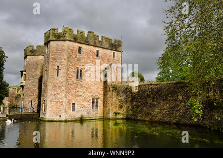 Sonne auf Bishop's Palace Torhaus mit Brücke über den Burggraben mit Swan und Enten bei bewölktem Himmel in Brunnen Somerset England Stockfoto