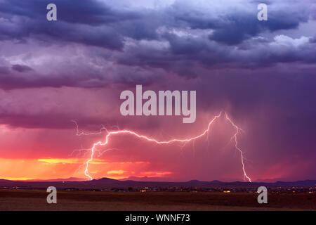 Ein Blitz bei Sonnenuntergang trifft durch dramatische Wolken, als sich ein Gewitter dem Chino Valley, Arizona, nähert Stockfoto