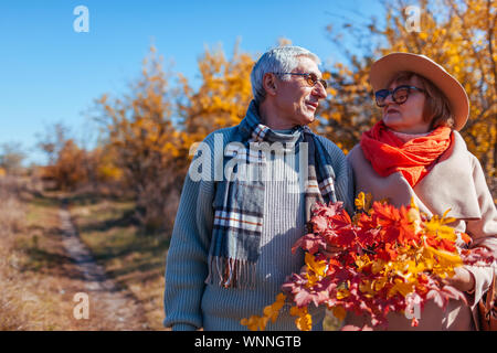 Senior Paar im Herbst Wald. Im mittleren Alter Mann und Frau chillen im Freien. Die Menschen reden und die Natur genießen. Zeit mit der Familie Stockfoto