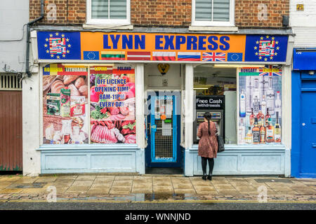 Frau mit einem kostenlosen Abhebungen am Geldautomat Lynn Express Osteuropäischen Supermarkt in King's Lynn, Norfolk. Stockfoto