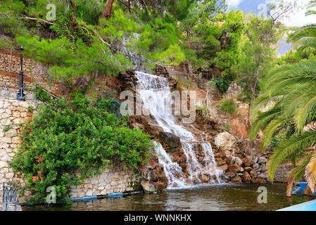 Ein grosser Wasserfall mit radon Wasser unter Felsbrocken am Fuß eines Berges in Loutraki, Griechenland. Stockfoto