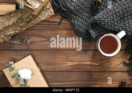 Herbst Komposition. Tasse Tee, Frauen Mode Schal, Geschenkbox, Brennholz, Holz- Hintergrund. Flach, Ansicht von oben, kopieren. Skandinavische hygge conce Stockfoto