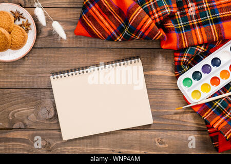 Ansicht von oben auf die Maler Arbeitsplatz mit Aquarell Palette, album, Frauen rote Mode Schal, Pinsel, Herbst getrocknete Blumen, Cookies. Herbst, Herbst, gemütliche Stockfoto