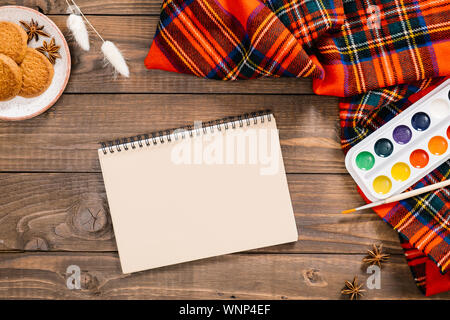 Ansicht von oben auf die Maler Arbeitsplatz mit Aquarell Palette, album, Frauen rote Mode Schal, Pinsel, Herbst getrocknete Blumen, Cookies. Herbst, Herbst, gemütliche Stockfoto