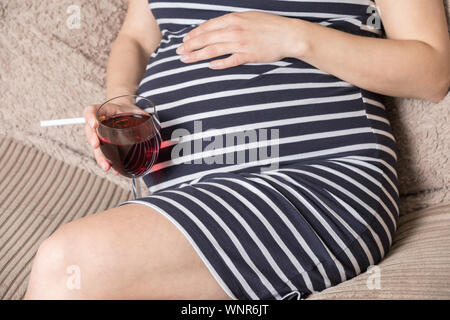 Schwangere Frau mit Zigarette und ein Glas Wein. Die Frau in der Schwangerschaft das Rauchen von Tabak und Alkohol Stockfoto