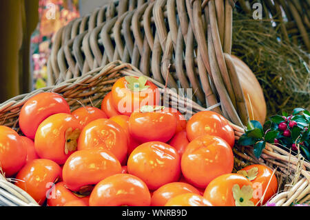 Orange Kaki auf Stroh in einem Weidenkorb. Stockfoto