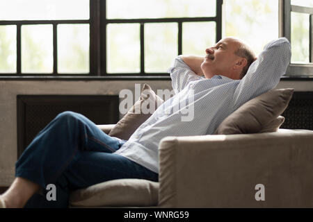 Happy senior Hispanic Mann entspannt auf einem Sofa zu Hause Stockfoto