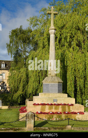 Weltkrieg I und II Memorial cross an der High Street auf dem Fluss Windrush in Bourton-on-the-Water Village in den Cotswolds England Stockfoto