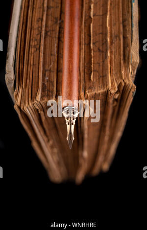 Alte Schrift - nib auf dem Hintergrund eines alten Buches. Zubehör für alte Briefe schreiben. Der dunkle Hintergrund. Stockfoto