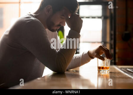 Betrunkener Mann allein sitzend Mit einem Glas Whiskey in bar vorgespannt Stockfoto