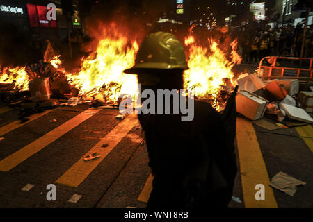 Kowloon, Hong Kong, China. 6. Sep 2019. Eine Demonstrantin Spaziergänge vor Brand, der durch die Demonstranten auf Freitag eingestellt wurde. Tausende von Demonstranten außerhalb von Mong Kok Polizeistation und um diesen Bereich sammelte die Polizei Gewalt gegen Bürger in Hongkong zu protestieren. Die Demonstranten zogen Nathan Rd nach Süden, Zerstören, Überwachungskameras, Straßenschilder, Barrikaden Bauen mit Holz- scheiben und Abfälle dann in Brand gesetzt, wie sie sich bewegt. Credit: Nakamura/ZUMA Draht/Alamy leben Nachrichten Stockfoto