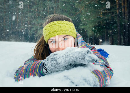 Das Mädchen liegt im Schnee und Lächeln Stockfoto