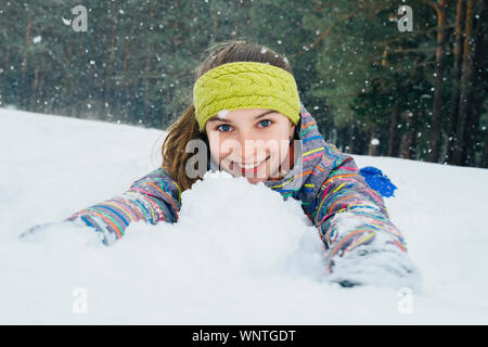 Mädchen liegt im Schnee und Lächeln Stockfoto