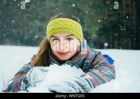 Das Mädchen liegt im Schnee und Lächeln Stockfoto