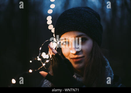 Nahaufnahme, Porträt der schönen jungen Frau mit Weihnachtsbeleuchtung Stockfoto
