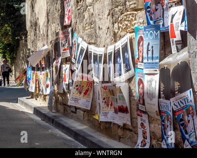 Junge Theaterliebhaber hängen Werbung für Leistungen in der Vorbereitung für das jährliche Festival von Avignon. Stockfoto