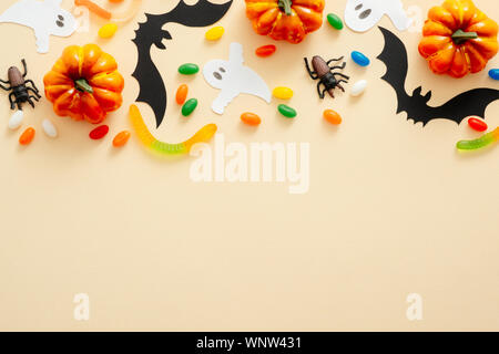 Halloween Komposition. Halloween Dekoration, Fledermäuse, Kürbisse, Süßigkeiten, Spinnen auf Pastell beige Hintergrund. Halloween Konzept. Flach, Ansicht von oben, Kopieren s Stockfoto