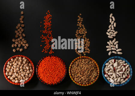 Rote und braune Linsen, Kichererbsen und weißen Bohnen sind Hülsenfrüchte, viel Protein enthalten, sind auf einem dunklen Hintergrund in Schalen entfernt, horizontal Stockfoto