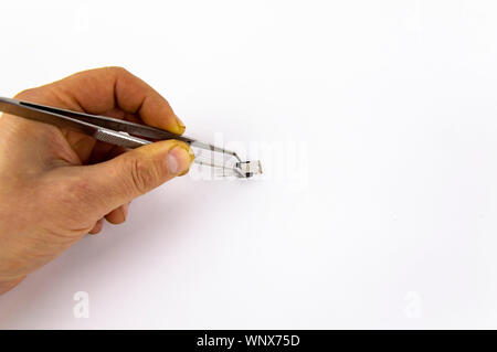 Werkzeug Pinzette in die Hand eines Mannes, auf weißem Hintergrund isoliert, es gibt einen kostenlosen Raum zu füllen Stockfoto