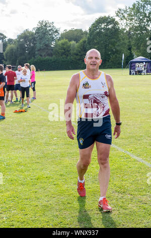 Ältere männliche Rugbyspieler (Alter 50-60) Spaziergänge in Richtung Kamera nach einem langen Tag Festival. Stockfoto