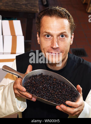 04. September 2019, Nordrhein-Westfalen, Bochum: Vater Justinus steht in der Distillery, die eine Messung der Schaufel mit Wacholderbeeren in die Hände und schauen in die Kamera des Fotografen, seine eigenen hohen Gin produzieren und nannte es "onatic Dry Gin". Die Kräuter, die er braucht, gepflanzt und im Klostergarten geerntet. Er erhält die Juniper aus der Toskana und die Körner, aus denen der erzeugte Alkohol ist, erhält er von der Mutter Abtei Heiligenkreuz im Wiener Wald. Im Kloster selbst er darf keinen Gin zu brennen, weil es keine Destillation Rechte haben. Fo Stockfoto