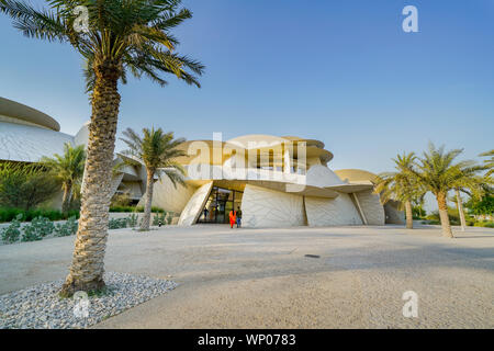 DOHA KATAR - 10 Juli 2019; Touristen eingabe National Museum von Katar am späten Nachmittag Sonne casting ein goldenes Leuchten über ungewöhnliche, aber markantes Design fo Stockfoto