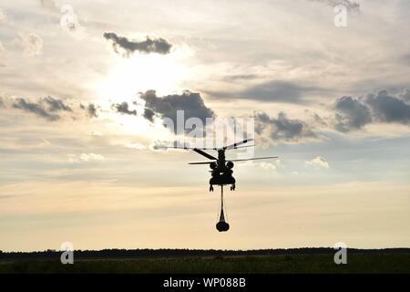 Eine CH-47 Chinook Hubschrauber, von Soldaten mit Bravo Company, 2-104 th Allgemeine Unterstützung Aviation Battalion, 28 Expeditionary Combat Aviation Brigade betrieben trägt Ladung durch die Schlinge - Belastung während einer updateauswirkungsanalyse Training, 25. Juni 2019. (U.S. Armee Foto von Sgt. Tyler Lane) Stockfoto