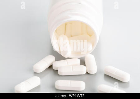 Eine Nahaufnahme einer Tablette Flasche mit ein paar weiße Antibiotikum Pillen. Vorderansicht, hellgrauen Hintergrund Stockfoto